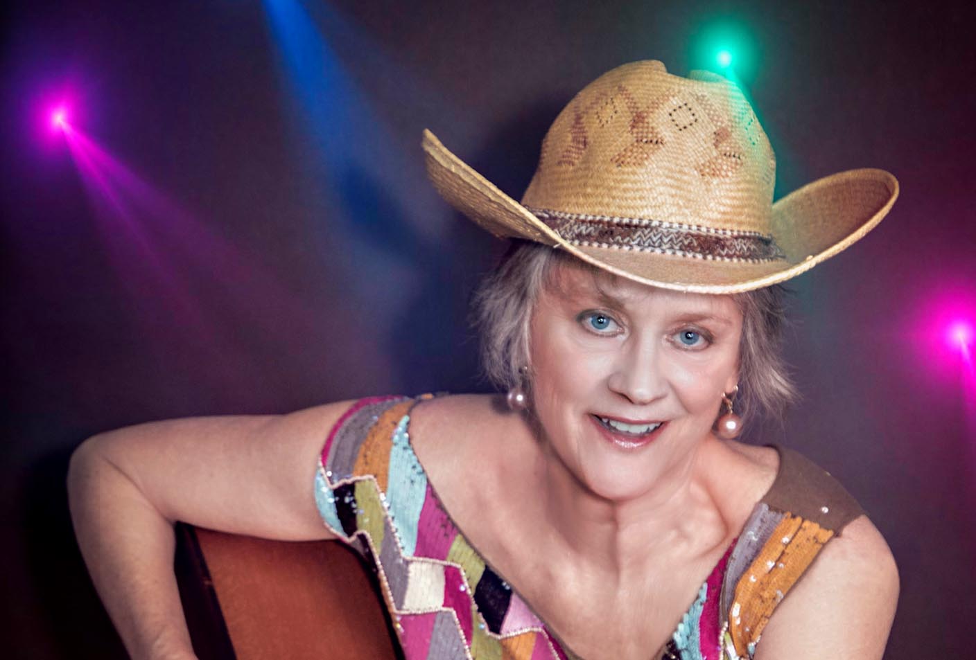 Jerialice Ars press headshot with cowboy hat and guitar